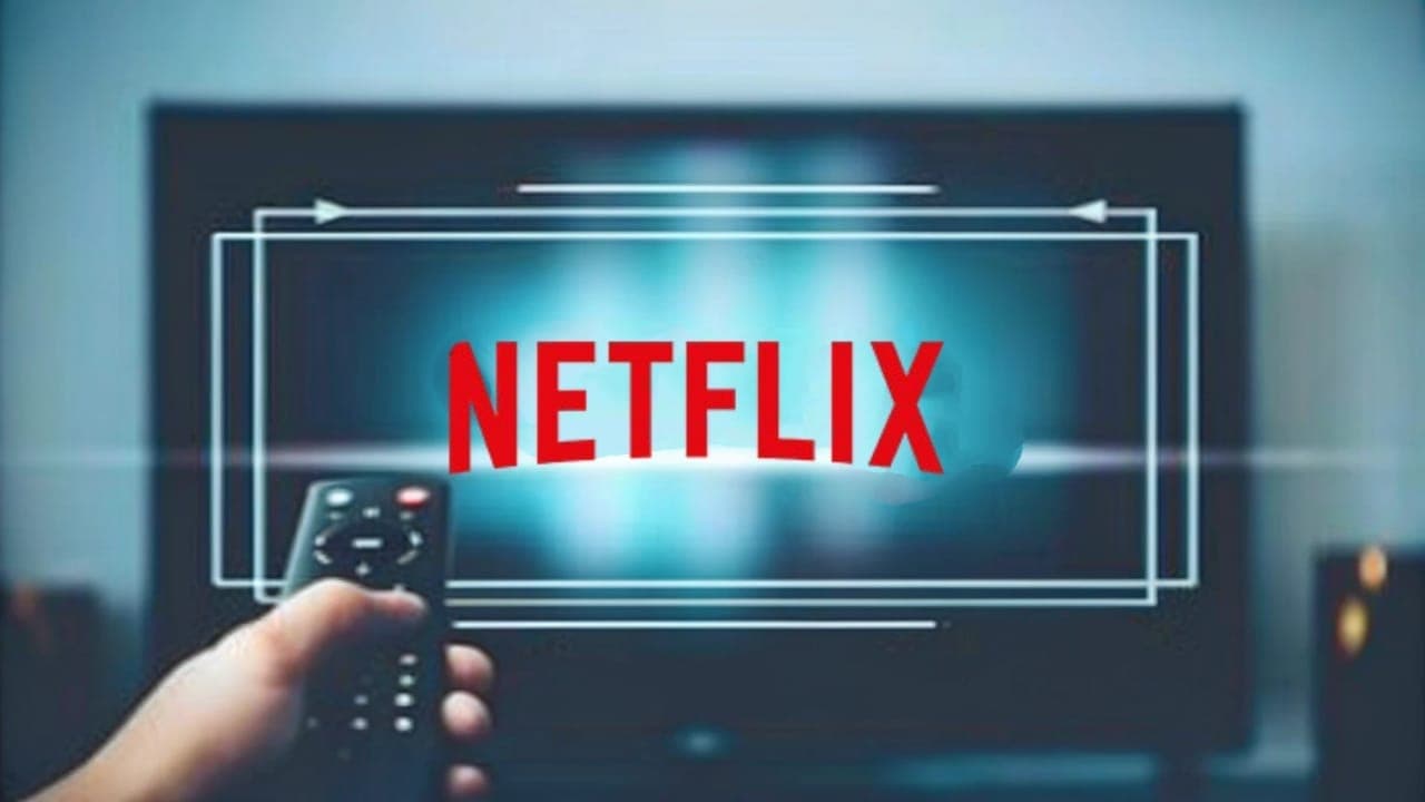 Hand holding a TV remote pointing at a screen showing the Netflix logo, symbolizing the new generative AI search powered by ChatGPT.